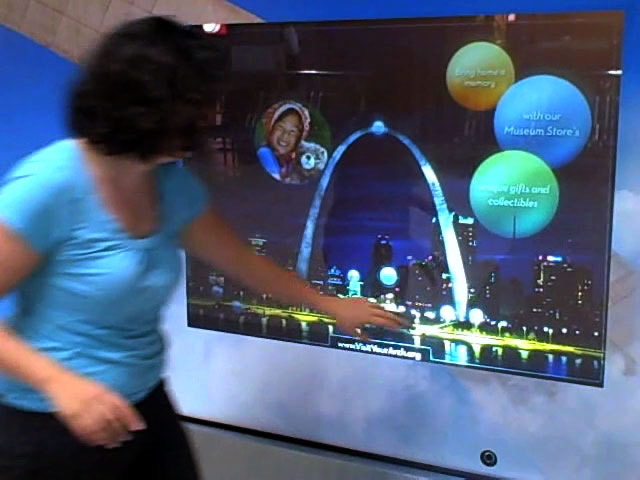 A visitor using an interactive wall showing the Gateway Arch